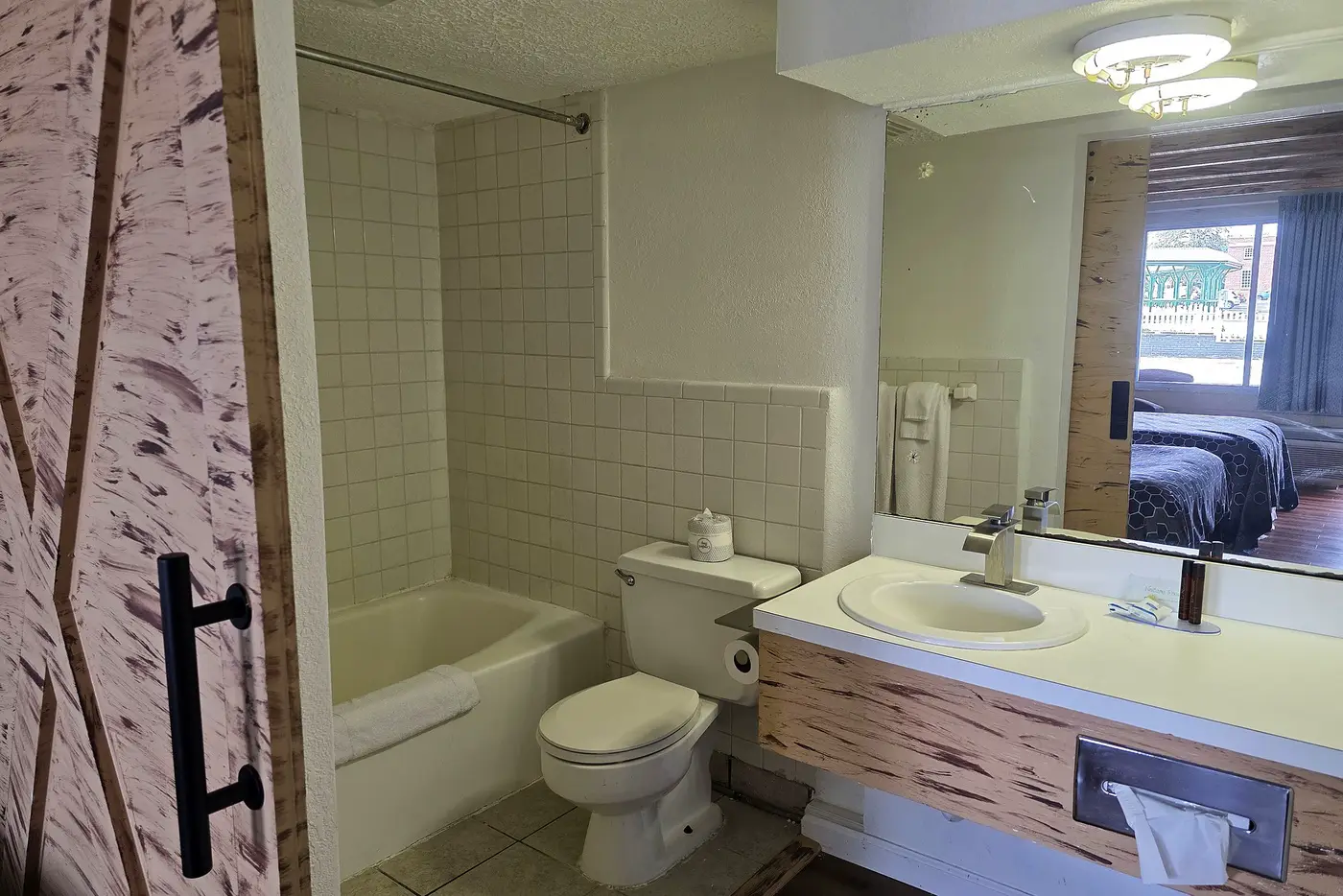 Guest bathroom with tub and shower behind a sliding weathered pine barn door