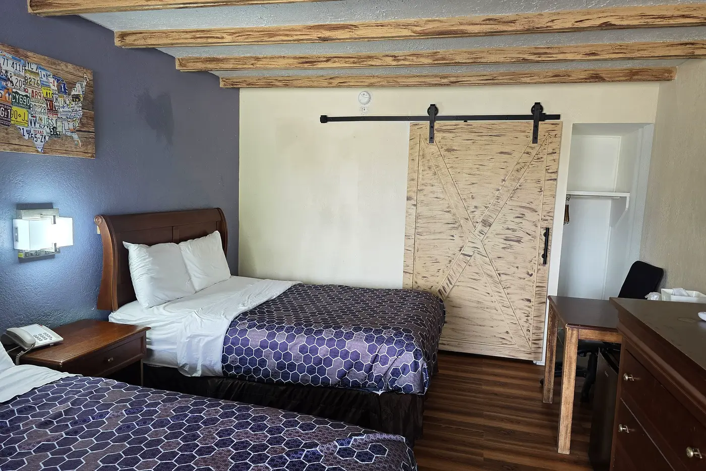 Guest room at Econo Lodge Galax with exposed timber ceiling beams, two beds and a sliding pine barn door